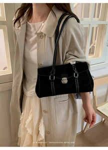 Detail of black rectangular suede shoulder bag with white contrast stitching and clasp
