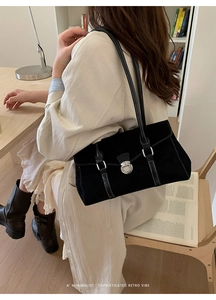 Close-up of black suede baguette bag with contrast white stitching and silver lock