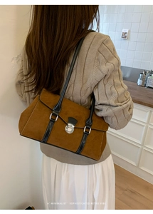 Detail of minimalist brown suede shoulder bag with retro flap and black leather straps