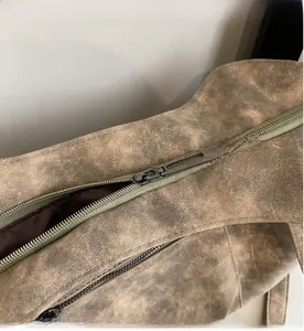Detailed close-up of smooth gray metal zipper and vintage leather texture on a tote bag