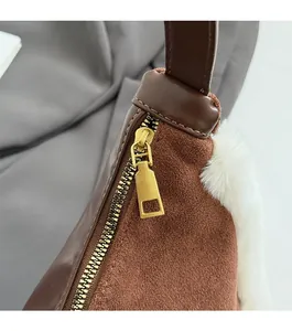 Detail of caramel suede crossbody bag featuring smooth leather stitching and golden zipper