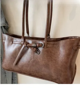 Detail view of retro brown tote bag featuring fine faux leather texture and dual metal buckles