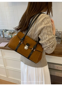 Detail showing brown suede shoulder bag with black leather straps and silver buckle