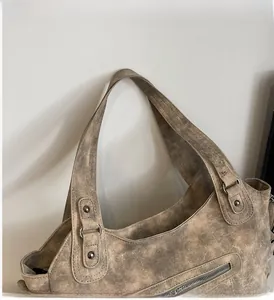 Detail of vintage tote bag featuring distressed brown leather texture and metal rivets