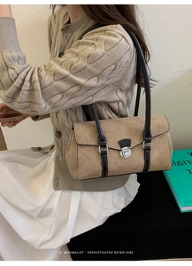 Close-up of khaki suede baguette bag with black leather trim and silver metal twist lock