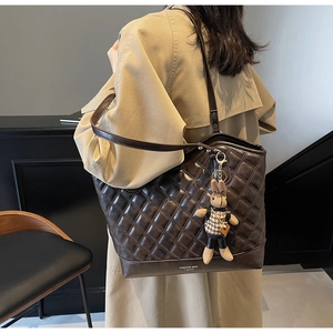 Macro detail of coffee brown quilted leather tote bag with cute bunny charm accessory