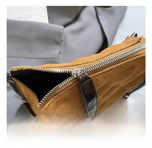 Macro detail of silver metal zipper and dark brown leather trim on suede handbag