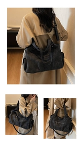 Detail of a large black vintage tote bag showing functional side pockets and adjustable strap