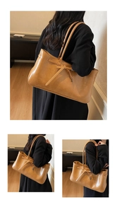 Detail of tan leather tote bag featuring sleek buckle strap and polished vintage texture