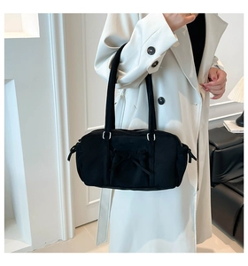 Detalle de bolso de lona negra con lazo decorativo y detalles de cordón lateral