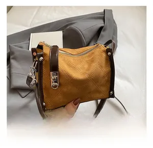 Detail of quilted suede crossbody bag with silver buckles and dark leather trim