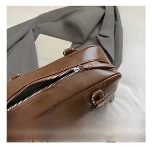 Detailed view of silver metal zipper and sturdy brown leather handles on a retro pillow bag