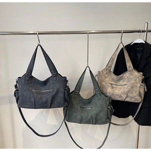 Three large tote bags in matte grey, green, and beige hanging on a rail for urban commuting