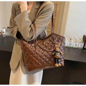 Detail of vintage quilted tote bag in dark brown PU leather with a cute bunny pendant