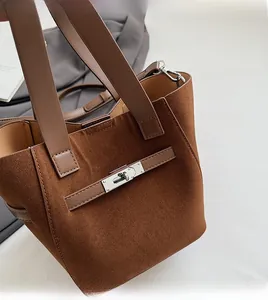 Detail of soft brown suede bucket bag featuring silver turn-lock and leather straps