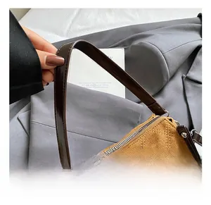 Detail of premium brown suede handbag featuring quilted texture and glossy leather handle