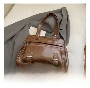 Detail of a dark brown vintage pillow bag with oiled finish and decorative buckles