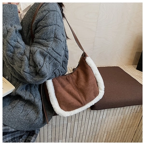 Close-up of brown suede shoulder bag with plush white faux fur trim and slender strap