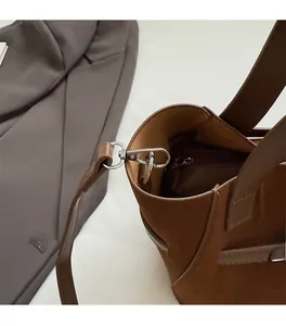 Detail of brown suede bucket bag featuring high-quality silver hardware and refined stitching