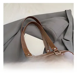 Detail showing smooth brown leather texture and silver rivets on the large tote bag handle