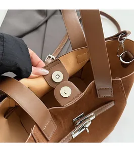 Detail view of the brown suede bucket bag featuring secure dual magnetic closures and silver lock