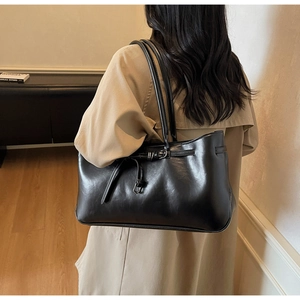 Detail of black glossy tote bag with leather texture and stylish shoulder strap detail