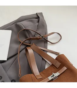 Close-up of brown faux leather bucket bag with elegant silver twist lock and shoulder strap