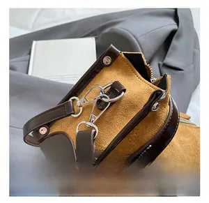 Close-up of high-quality metal carabiner clasp and rivet details on yellow suede bag