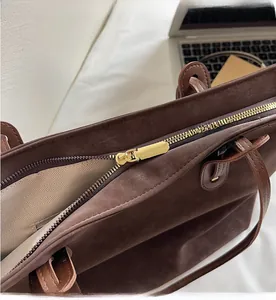 Close-up of smooth gold metal zipper and herringbone lining on vintage brown tote bag