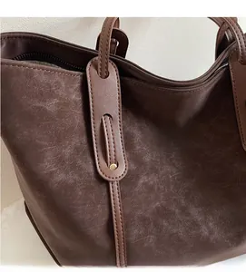 Detail of dark brown leather tote bag with vintage texture and rivet reinforcement