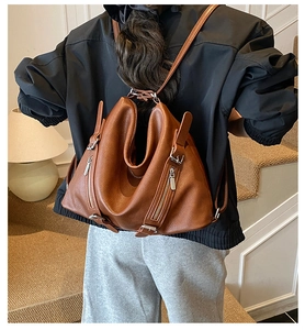 Rear view of model wearing a brown leather lindy-style backpack in a minimalist indoor setting