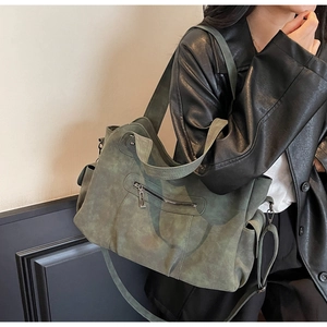 Detail of dark green vintage tote bag showing matte texture and functional zipper pockets