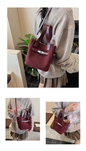 Detail of burgundy faux suede bucket bag featuring polished metal twist lock and dual textures