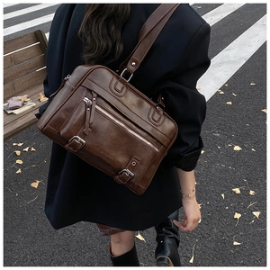 Detail of vintage brown leather shoulder bag featuring silver zippers and buckle accents