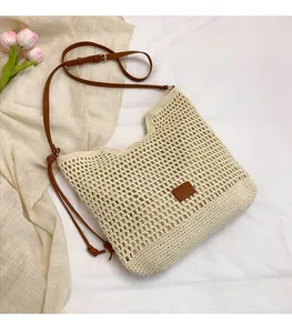 Detail of hand-crocheted cream woven bag featuring adjustable brown leather shoulder strap