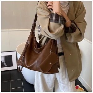 Detail of vintage brown tote bag with decorative tassel and adjustable strap