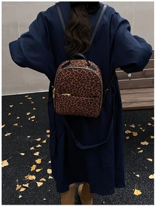 Detailansicht eines kompakten Leoparden-Rucksacks getragen mit einem langen Herbstmantel