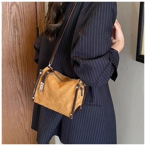 Brown suede crossbody bag with rhombus stitching shown on a model in a navy suit
