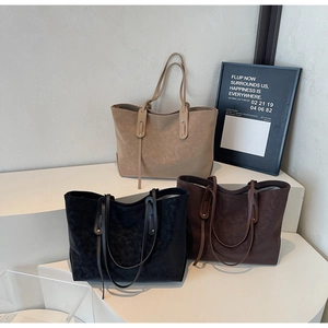 Three minimalist large tote bags in black, dark brown, and beige displayed on stands