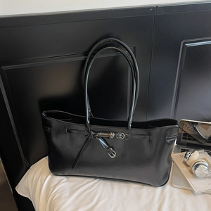 Detail of black matte leather tote bag with stylish buckle strap and dual slim handles