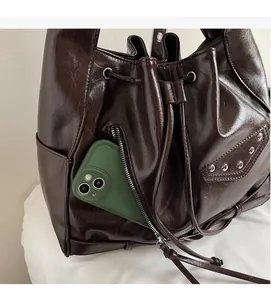 Detail of vintage brown leather bucket bag showing zipper pocket and silver stud accents