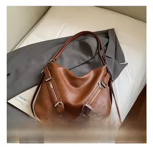 Detail showing the brown leather texture and metal zipper accents on the tote bag