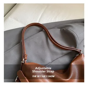 Close-up of adjustable shoulder strap and silver hardware on brown lychee leather tote bag