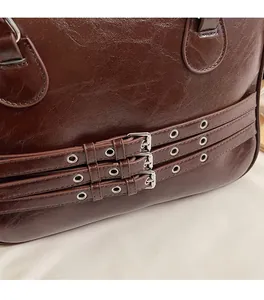 Detail of dark brown leather tote featuring vintage cracked texture and silver buckles