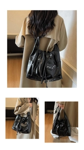 Detail view of black vintage bucket bag featuring silver studs and decorative zippers