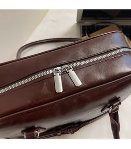 Detail of smooth metal zippers on brown glossy leather shoulder bag for women