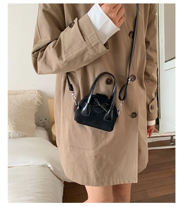 Detalle de mini bolso negro bandolera con lazo y paneles de cuero texturizado