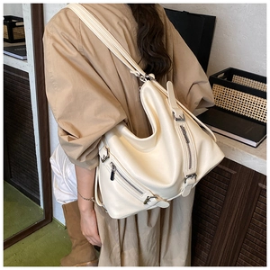 Detail view of large cream motorcycle style tote bag with silver zippers and wide strap