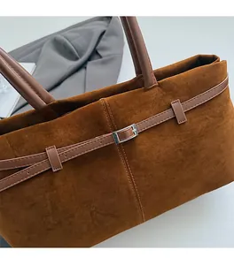 Gros plan d'un sac cabas en daim marron avec boucle argentée et détails en cuir
