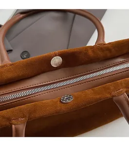 Détail du sac cabas en daim marron foncé montrant la fermeture éclair et la boucle magnétique
